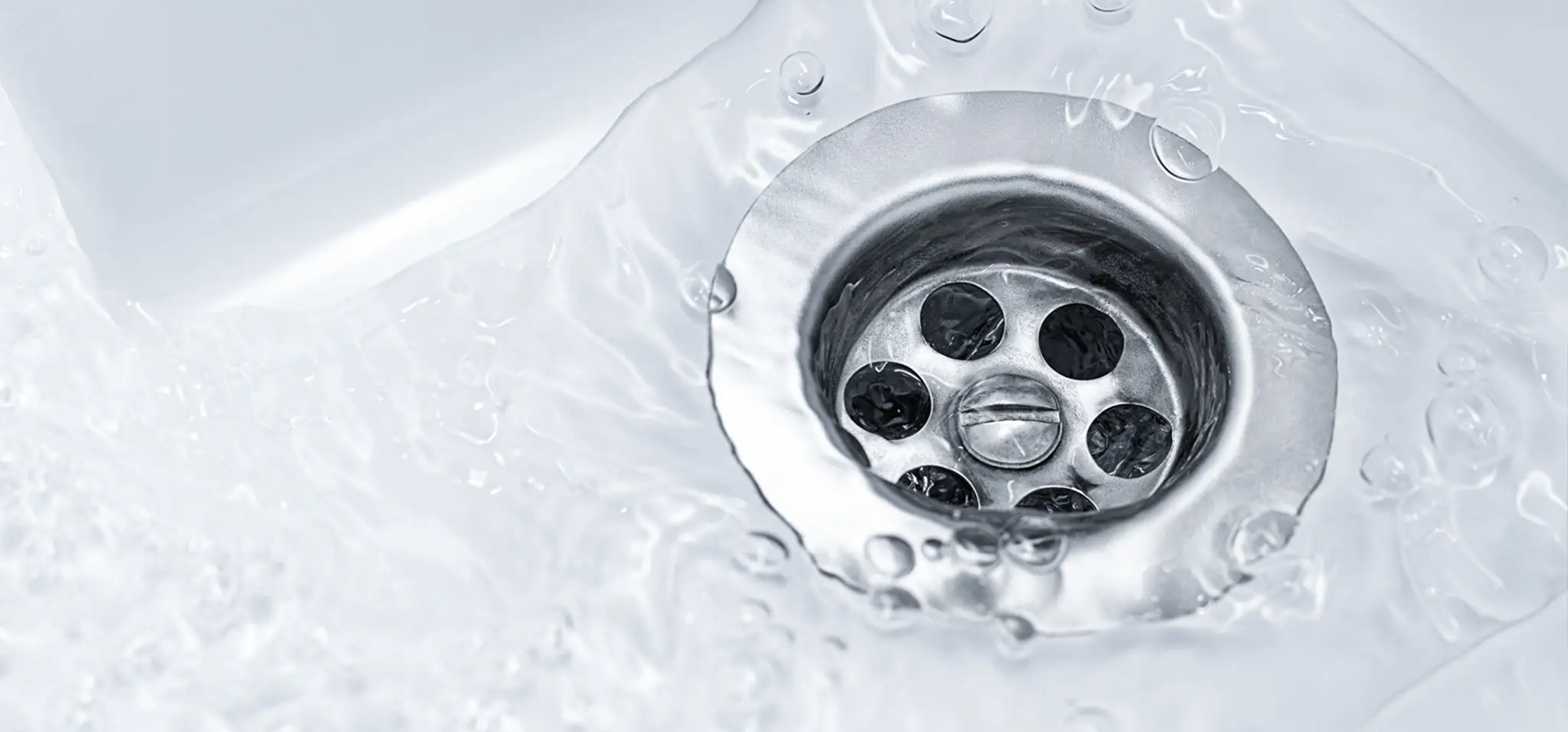 Water flowing down a metal drain in a sink.