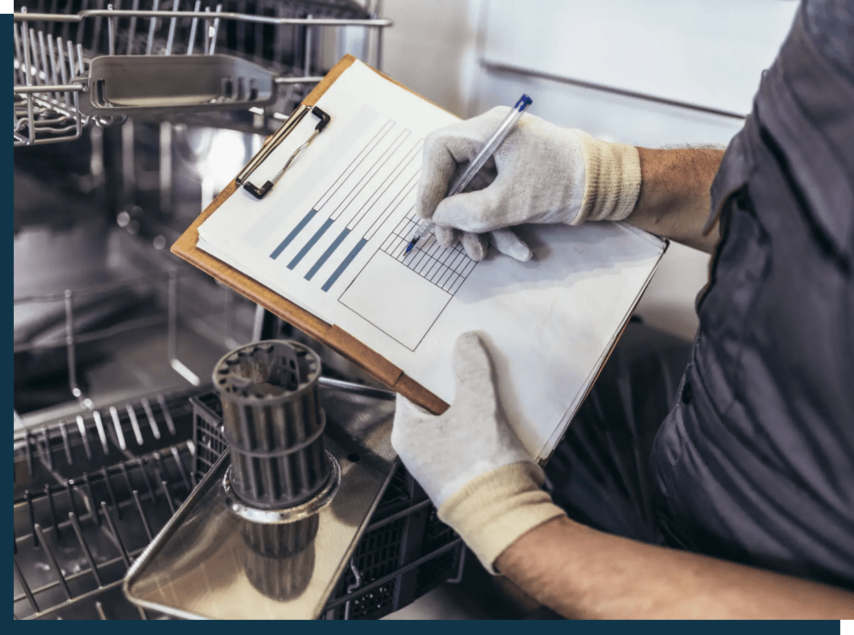 A person in gloves holding a clipboard and pen near industrial equipment.