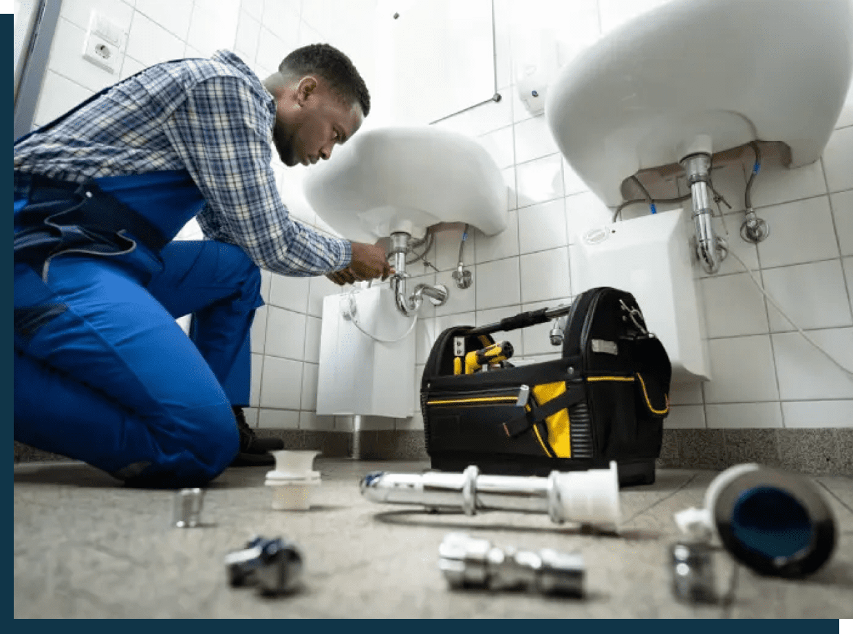 A plumber fixing a bathroom sink with tools scattered around.
